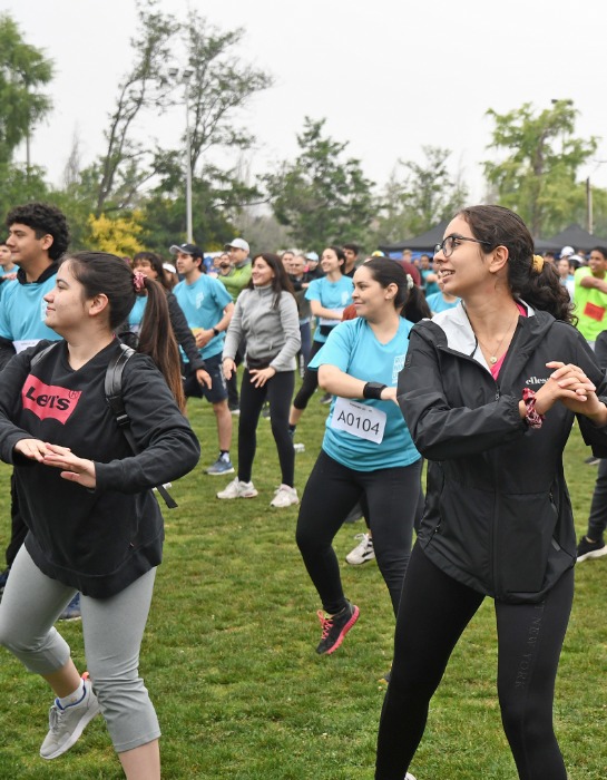 Grupo de personas y estudiantes de la Comunidad UC participan de actividad física al aire libre al interior del campus San Joaquín.