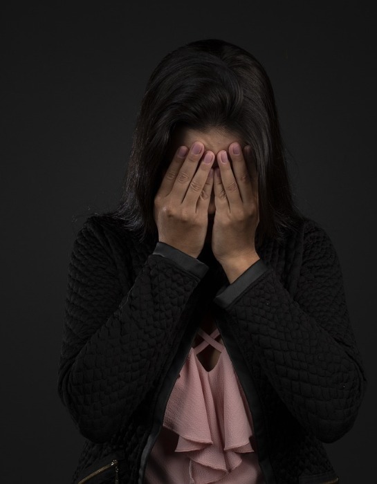 Imagen muestra a mujer tapándose la cara con sus manos en clara señal de estrés y/o depresión.