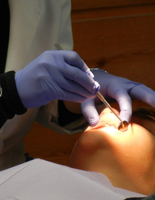 Imagen muestra a odontólogo realizando procedimiento dental a paciente.