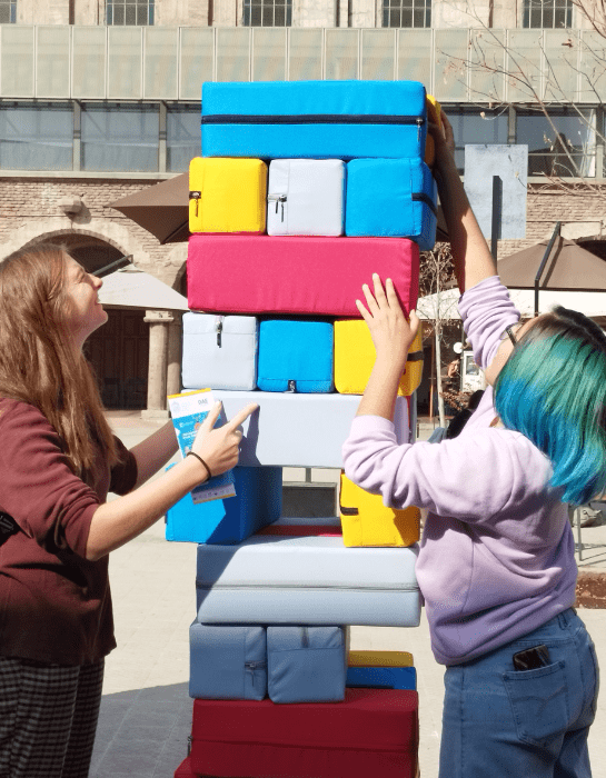 Estudiantes sonrientes jugando con un yenga de tamaño grande de colores